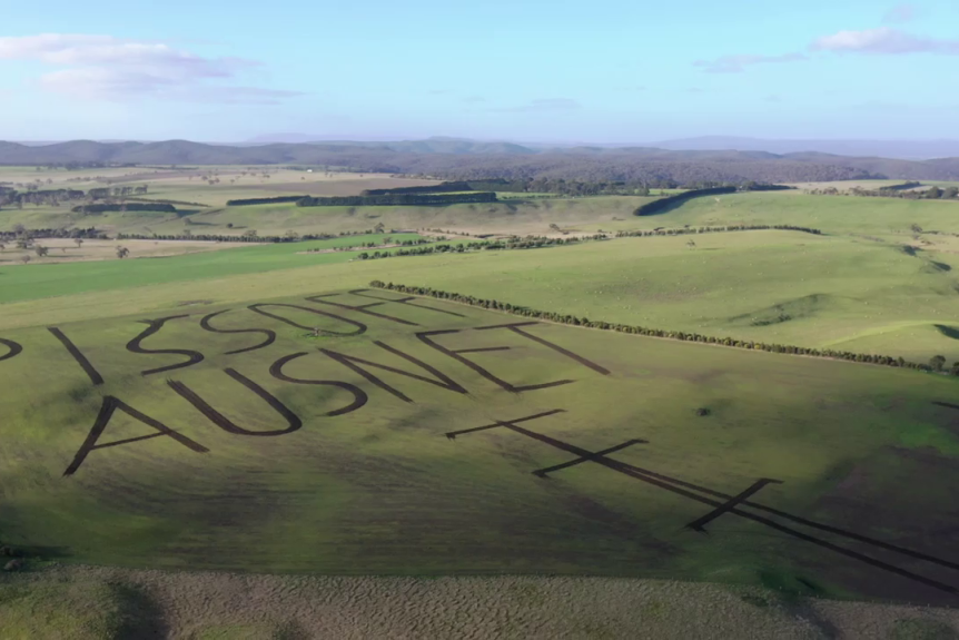 A drone photo of a western Victorian farm with a crude message written on it